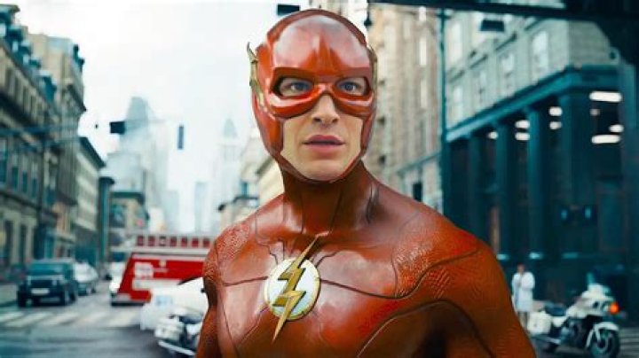 Flash (Ezra Miller), in a T-shirt and hoodie, sits in his childhood bedroom as blue lightning crackles through his body in The Flash